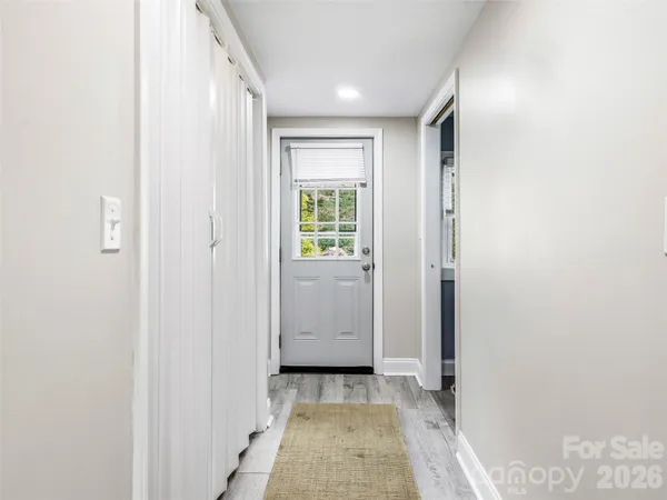 a view of a hallway with wooden floor and a bathroom