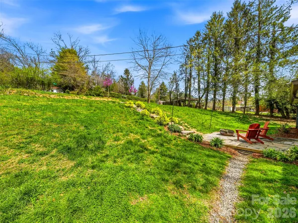 a view of a house with a big yard potted plants and large tree