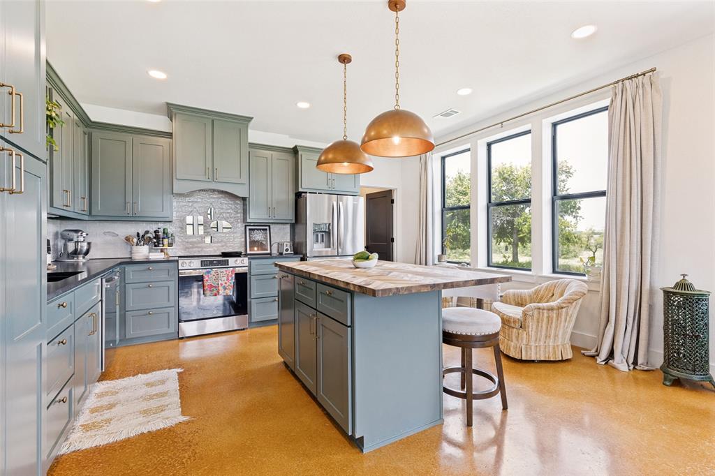 490 Private Road 4512 Decatur, TX 76234 - Photo 8 of 27 Spacious kitchen featuring sage cabinetry, stainless steel appliances, a center island with seating, and ample natural light from multiple windows