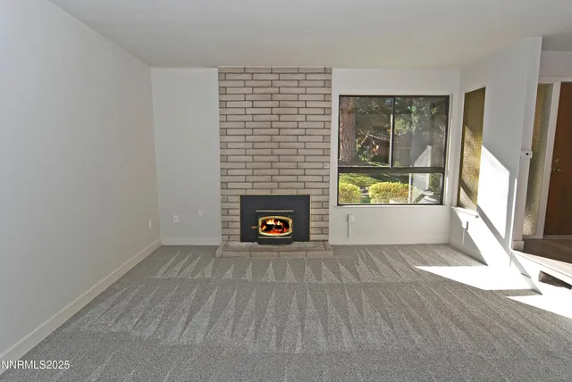 a view of an empty room with a fireplace and a window