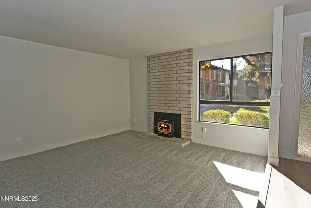 a view of an empty room with a fireplace and a window