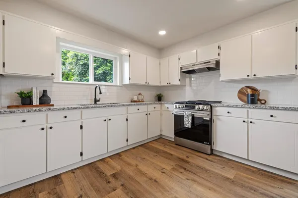 a kitchen with white cabinets white appliances and sink