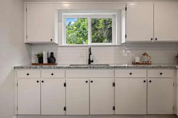 a kitchen with granite countertop white cabinets and a window