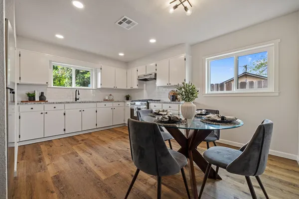 a kitchen with a dining table chairs and white cabinets