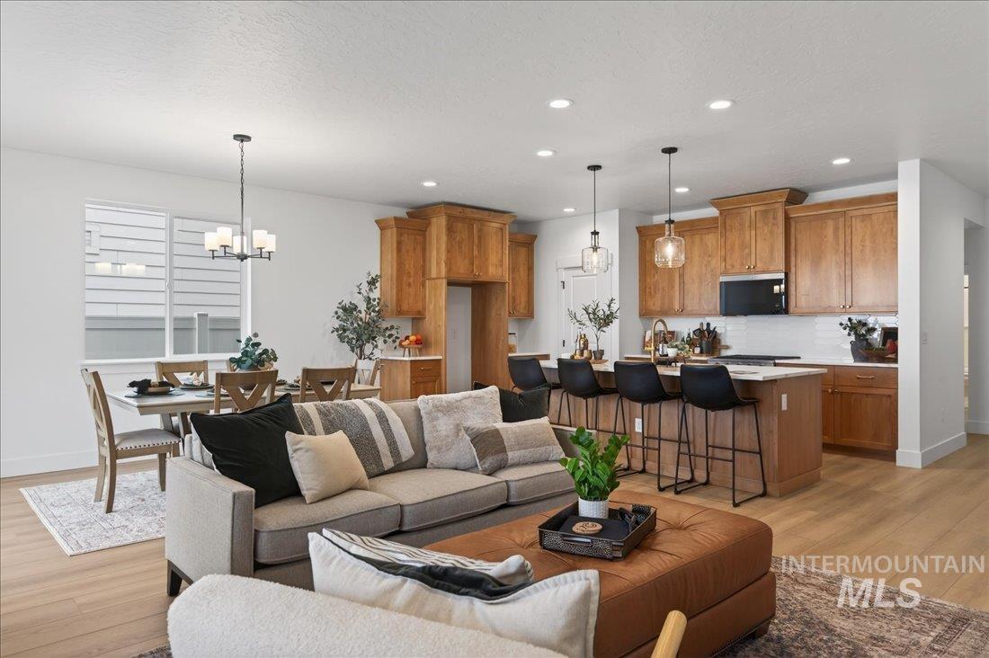 1268 West Swift Fox Street Meridian, ID 83642 - Photo 4 of 34 Living room featuring light wood-type flooring, a chandelier, a textured ceiling, and recessed lighting