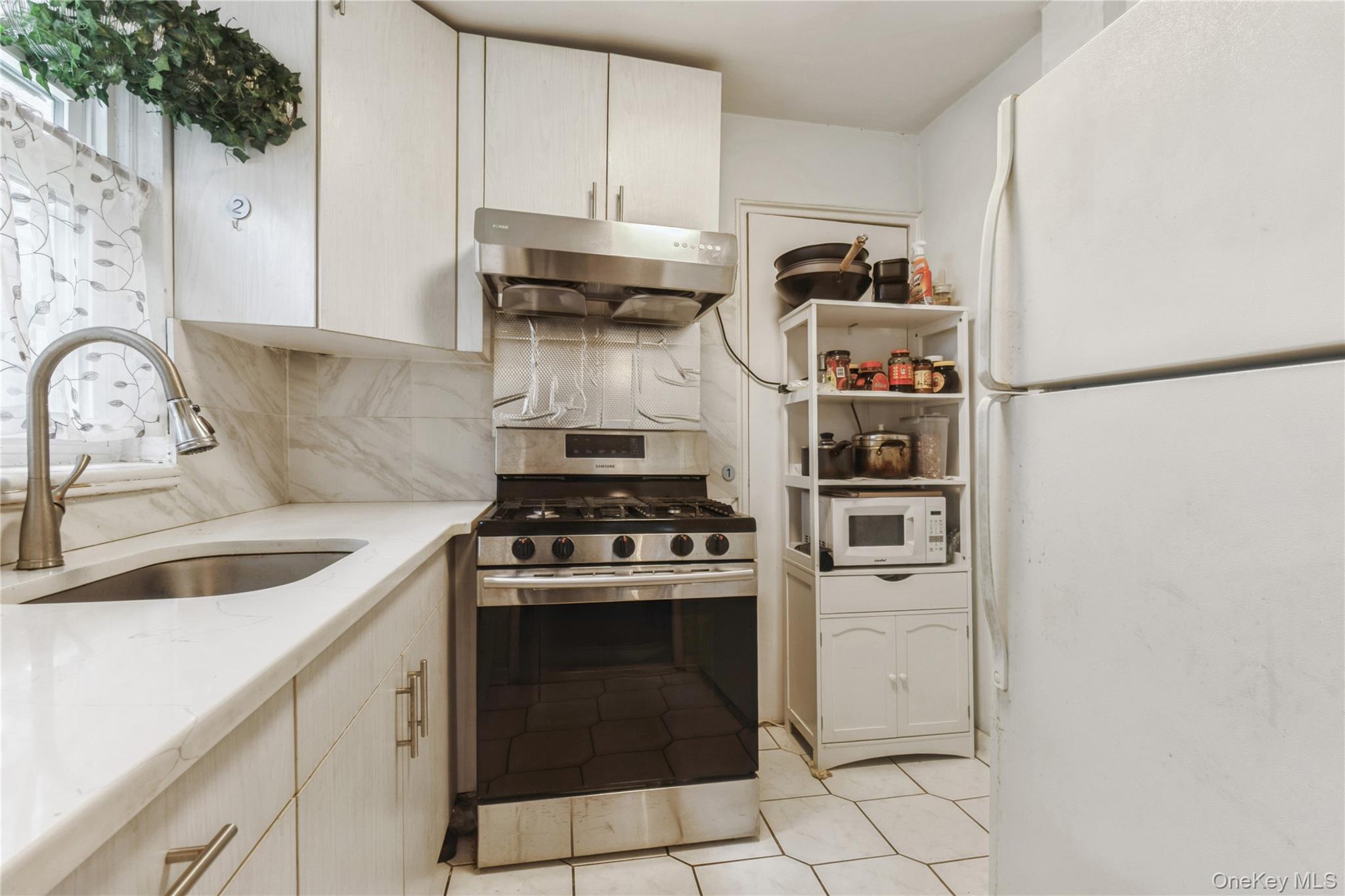 147-57 Charter Road, Unit 26D Queens, NY 11435 - Photo 16 of 21 Kitchen featuring white appliances, extractor fan, decorative backsplash, light tile patterned floors, and light stone countertops