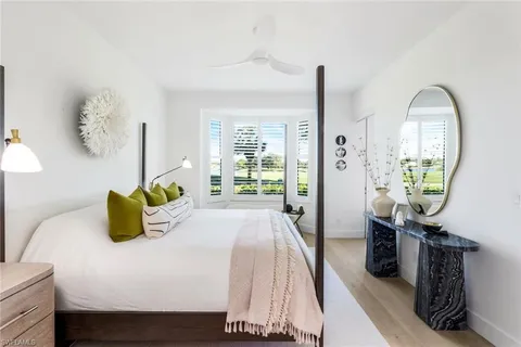 a bedroom with a bed a window and painting on the wall