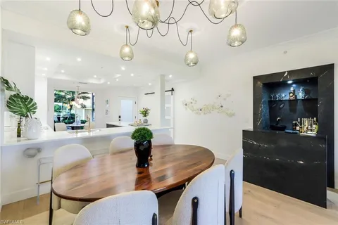 a dining room with wooden floor a chandelier a wooden table and chairs