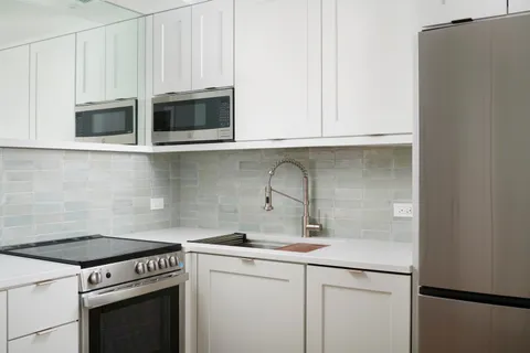 a kitchen with stainless steel appliances granite countertop white cabinets a stove a sink and dishwasher