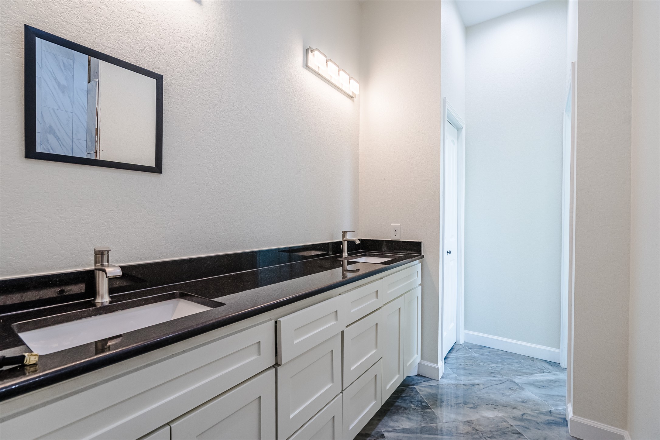 1354 Old Pin Oak Road Paige, TX 78659 - Photo 17 of 37 The bathroom features a double vanity with dark countertops and white cabinetry, complemented by a large mirror and modern light fixtures