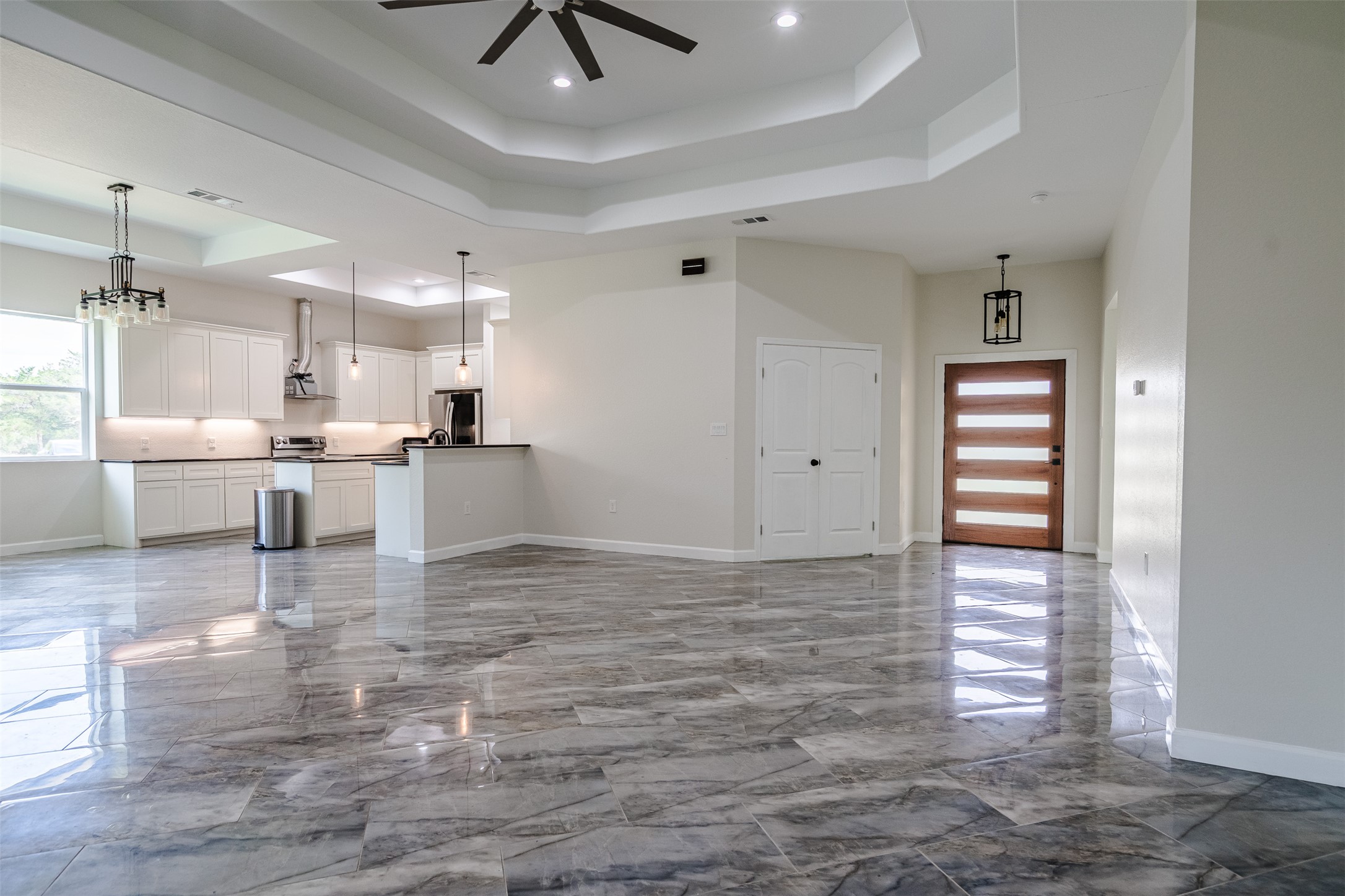 1354 Old Pin Oak Road Paige, TX 78659 - Photo 21 of 37 Expansive open-concept living area featuring polished marble-effect floor tiles, a modern kitchen with white cabinetry, and a decorative ceiling fan