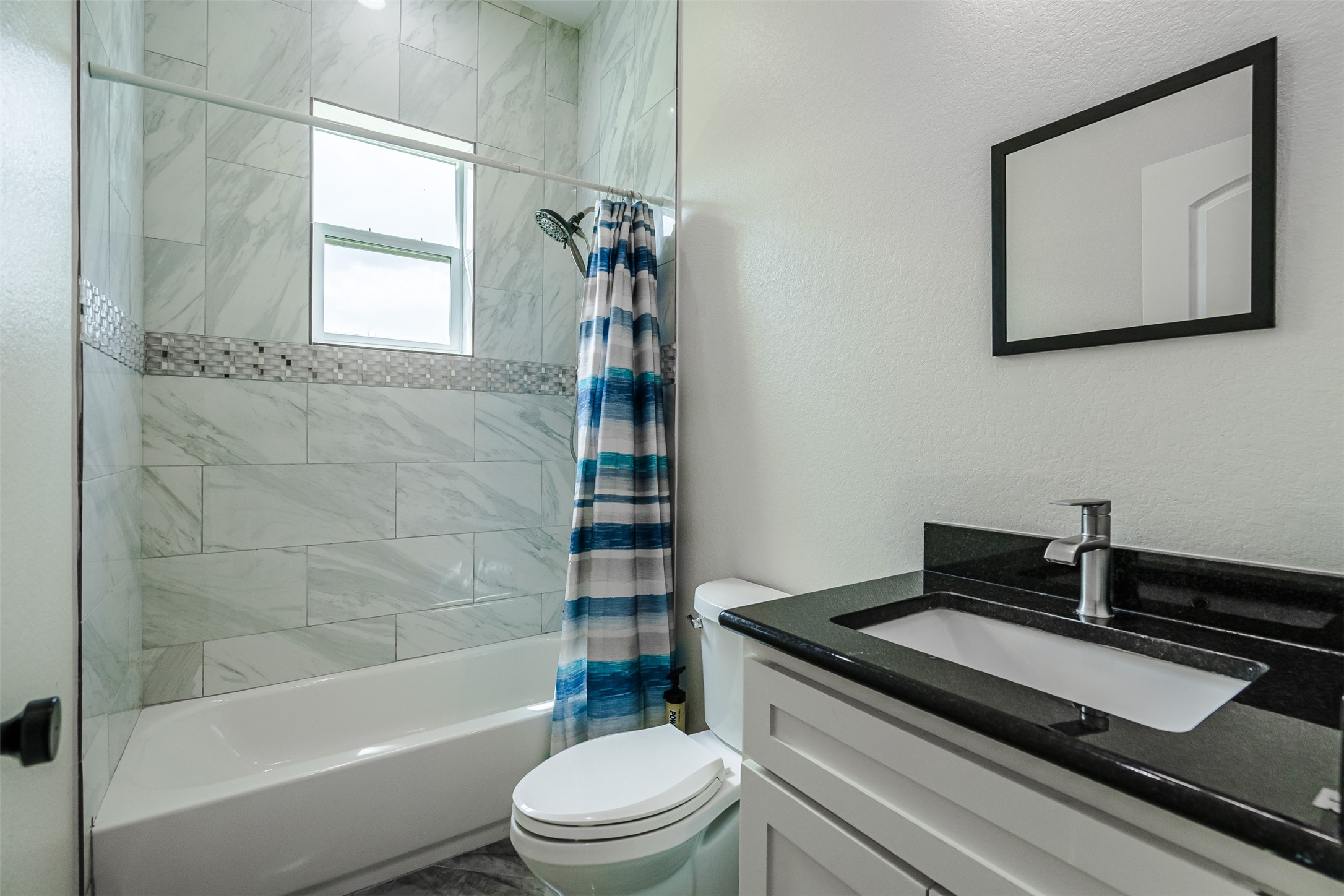 1354 Old Pin Oak Road Paige, TX 78659 - Photo 23 of 37 Bathroom featuring a white bathtub, a tiled shower surround with decorative accent tile, and a vanity with a dark countertop and an undermount sink