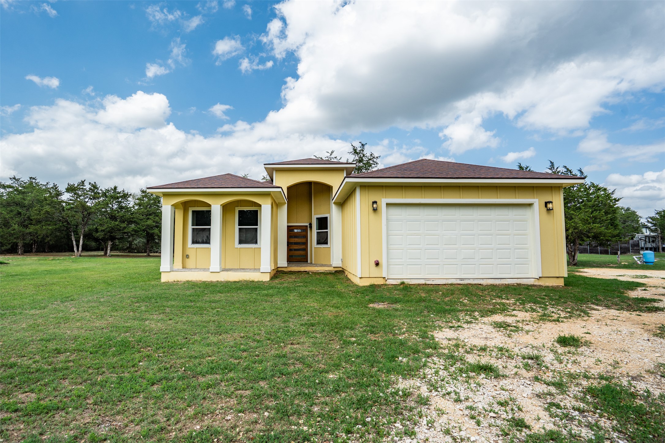 1354 Old Pin Oak Road Paige, TX 78659 - Photo 5 of 37 a view of a white house next to a yard with big trees