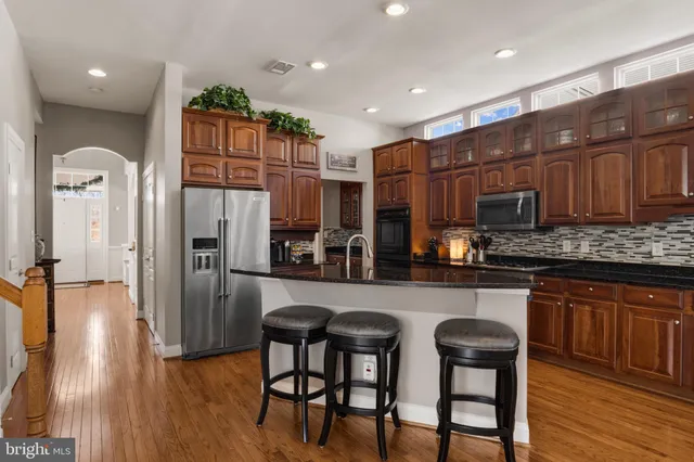 a kitchen with stainless steel appliances granite countertop a refrigerator a stove top oven a sink and cabinets