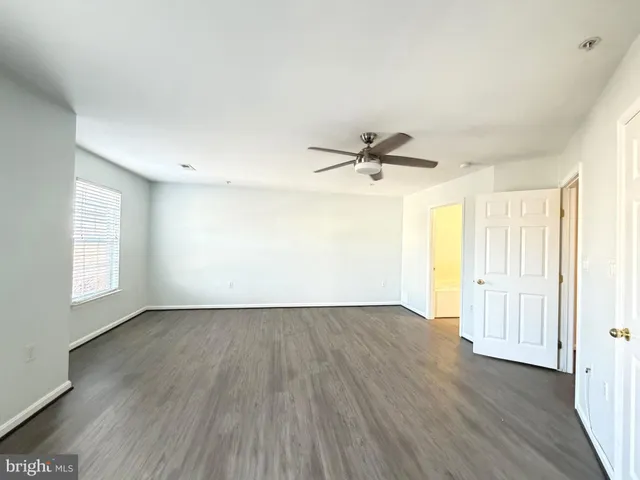 an empty room with wooden floor fan and windows