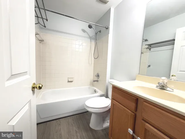 a bathroom with a granite countertop bathtub shower sink vanity and toilet