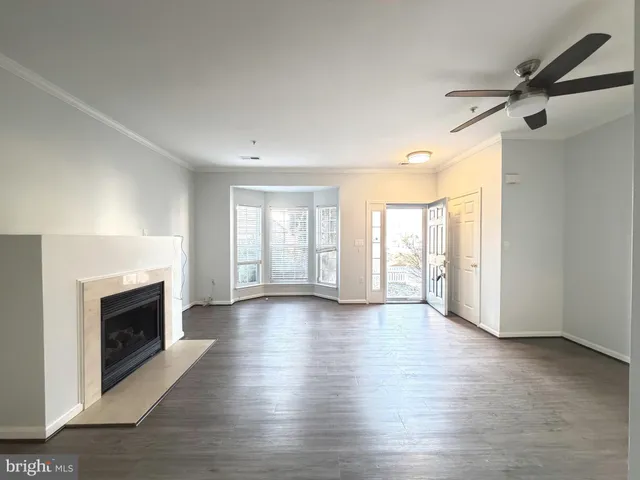 an empty room with wooden floor fireplace and windows