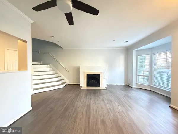 an empty room with wooden floor fireplace and windows