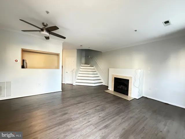 an empty room with wooden floor fireplace and windows