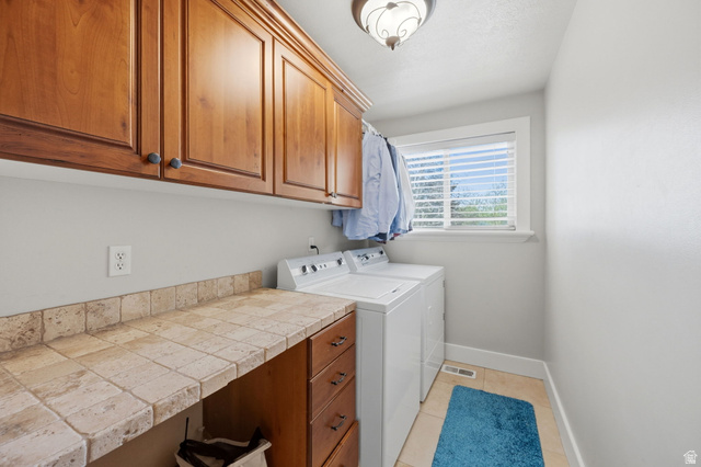1683 North Main Street Centerville, UT 84014 - Photo 13 of 37 Dedicated laundry space featuring upper and lower wood cabinetry, a tiled countertop, and a window with blinds