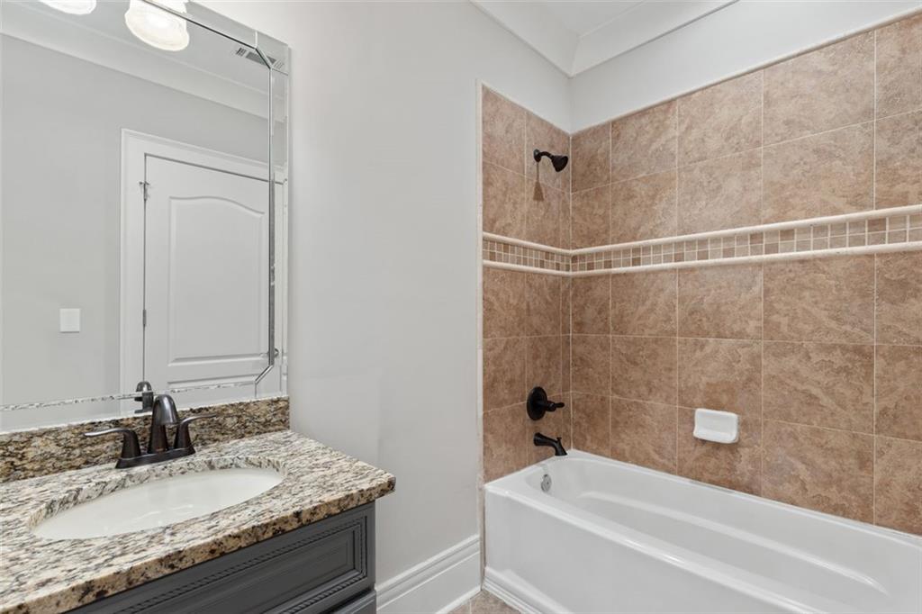 6509 Lily Trail Fairburn, GA 30213 - Photo 52 of 117 a bathroom with a granite countertop sink a mirror and a bathtub
