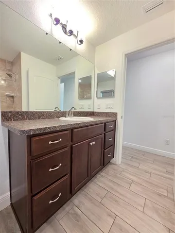 a spacious bathroom with a granite countertop sink and a mirror