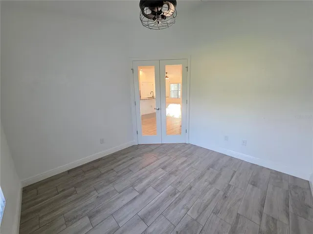 an empty room with wooden floor and windows