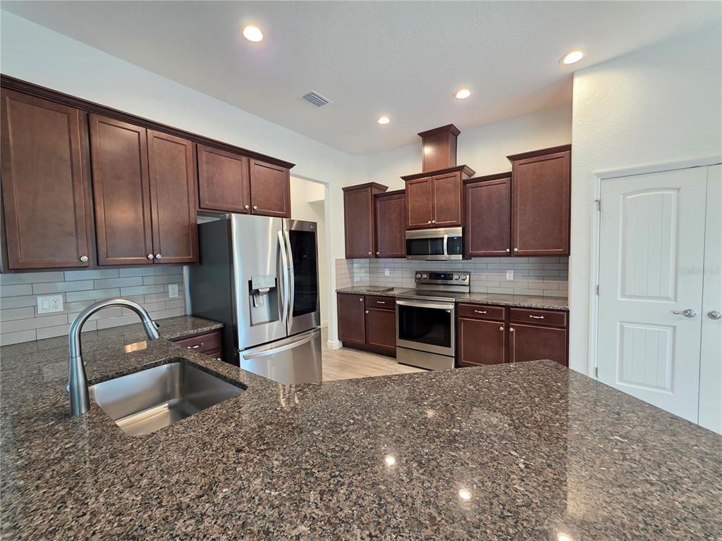 11240 Marvelwood Road Weeki Wachee, FL 34614 - Photo 2 of 21 a kitchen with stainless steel appliances granite countertop a refrigerator sink and stove