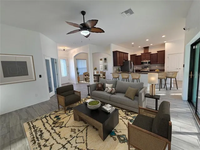 a living room with furniture kitchen view and a wooden floor