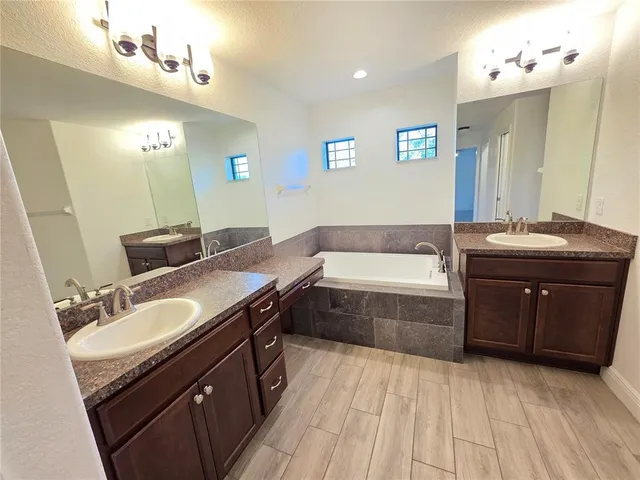 a spacious bathroom with a granite countertop sink a mirror a bathtub and shower