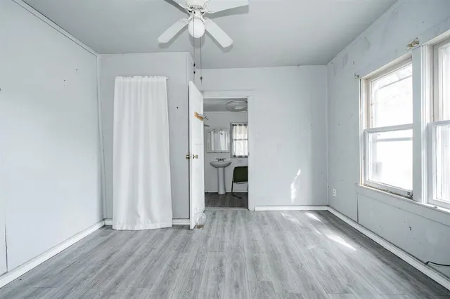 an empty room with wooden floor chandelier and windows