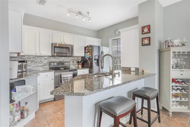 a kitchen with kitchen island granite countertop a sink cabinets and stainless steel appliances
