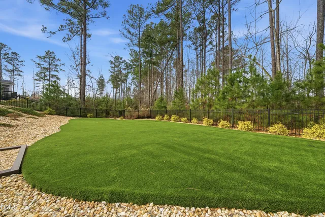 an aerial view of a house with garden space and trees in the background