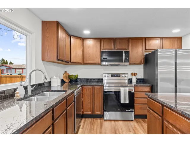 a kitchen with kitchen island granite countertop a stove sink microwave and refrigerator
