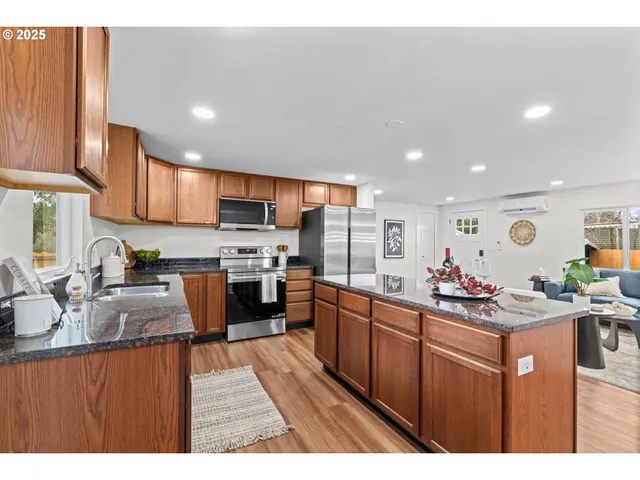 a kitchen with stainless steel appliances kitchen island granite countertop a stove sink and cabinets