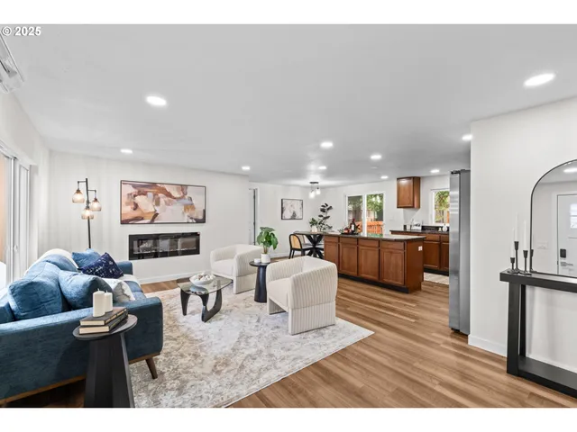 a living room with furniture kitchen view and a wooden floor