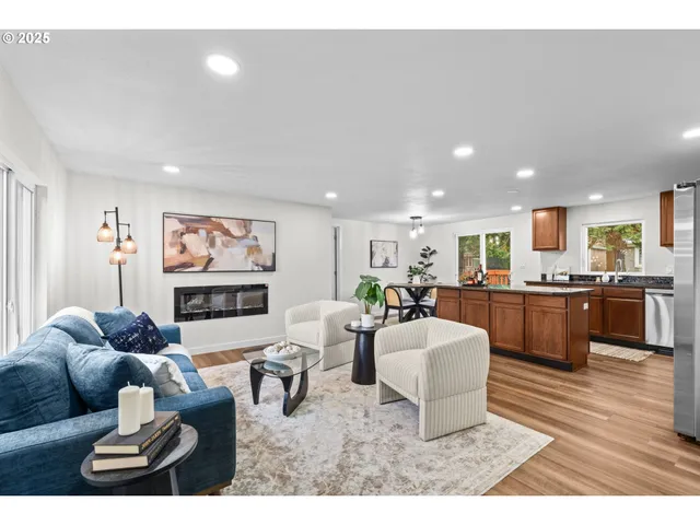 a living room with furniture a kitchen view and a wooden floor
