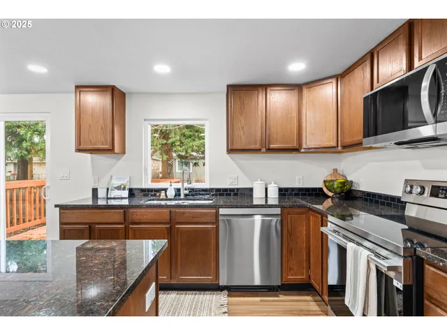a kitchen with stainless steel appliances granite countertop a stove a sink a microwave and refrigerator