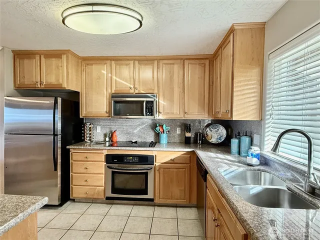 a kitchen with stainless steel appliances a sink a stove a refrigerator cabinets and a dining table
