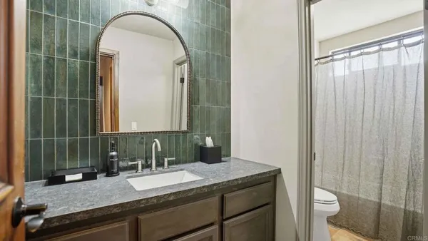 a bathroom with a granite countertop sink a toilet and a mirror