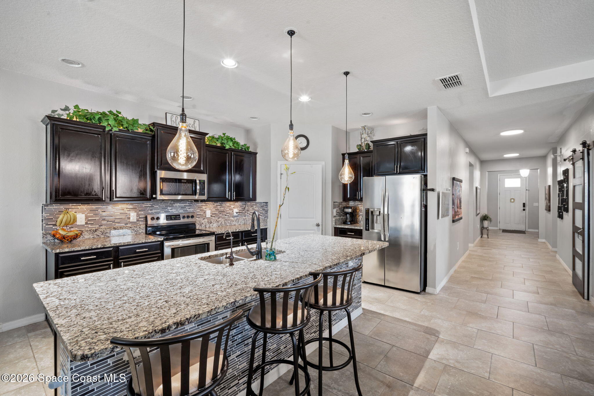1941 Partin Terrace Road Kissimmee, FL 34744 - Photo 3 of 36 a kitchen with stainless steel appliances kitchen island granite countertop a kitchen island and chairs in it