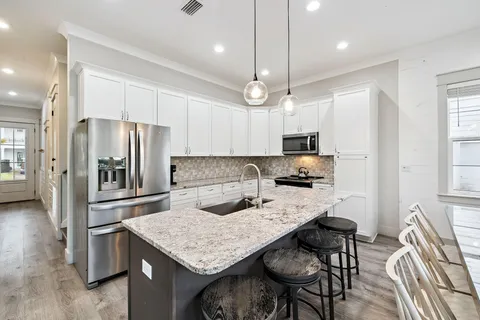 a kitchen with stainless steel appliances granite countertop a stove a kitchen island a dining table and chairs