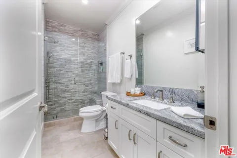 a bathroom with a granite countertop sink a toilet and a mirror
