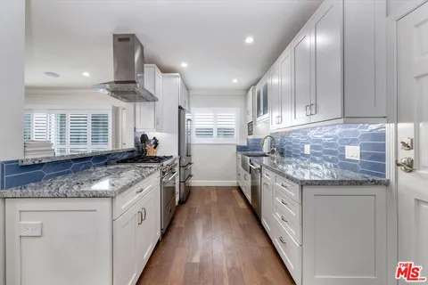 a kitchen with granite countertop kitchen island stainless steel appliances a sink stove and cabinets