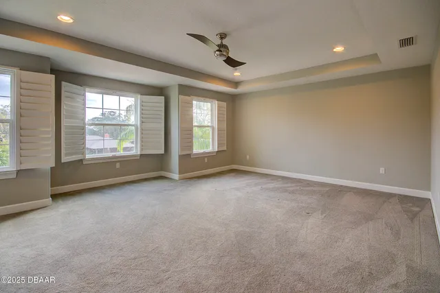 an empty room with windows and ceiling fan