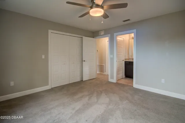 an empty room with chandelier fan and windows