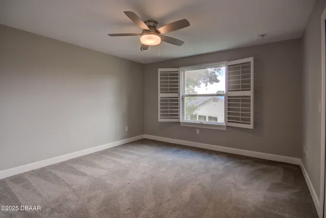 an empty room with windows and fan