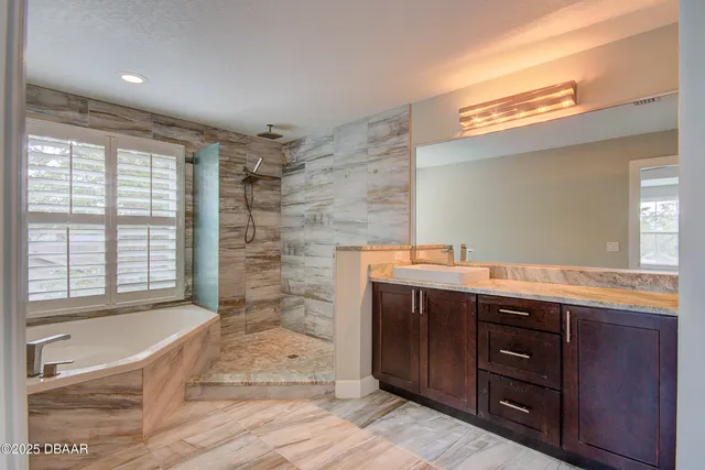a spacious bathroom with a granite countertop sink mirror and bathtub