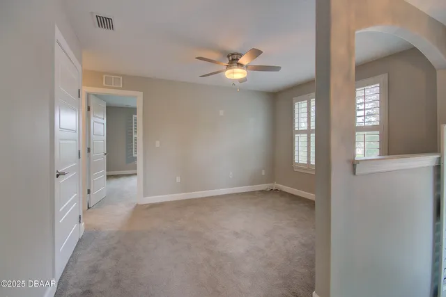 a view of an empty room with chandelier fan and window