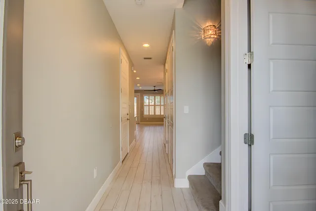 a view of a hallway with wooden floor and a bathroom